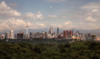 Unfiltered realistic aerial sky view of Kuala Lumpur skyline buildings at a distance, with trees...