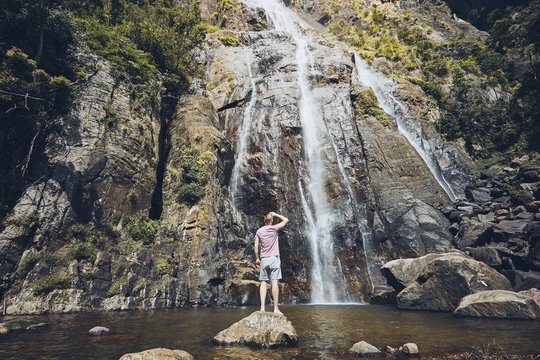 Man standing against waterfall