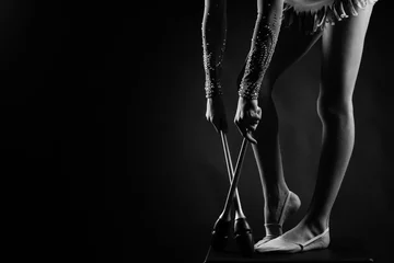 Poster Teenager girl gymnast holds in hands clubs for rhythmic gymnastics.near the legs © Rakursstudio