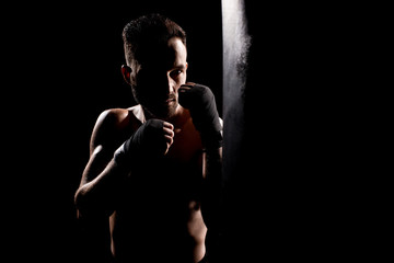 Fototapeta na wymiar shortless athlete hitting punching bag isolated on black