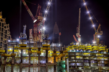 Building skyscraper at construction process during night.