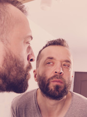 Man looking at beard in mirror