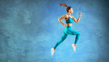 Fototapeta na wymiar Young woman runner in turquoise sportswear jump in the air.