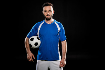 bearded football player standing with ball isolated on black