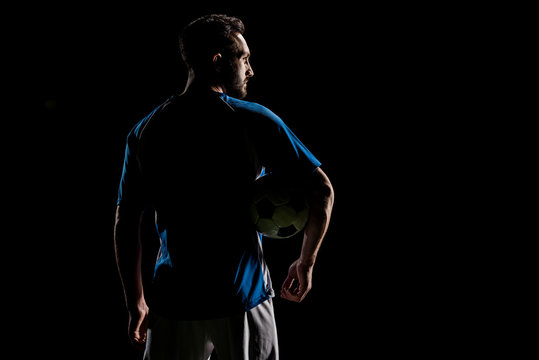 silhouette of muscular sportsman holding ball isolated on black