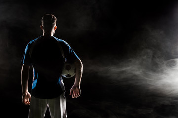 silhouette of man standing in uniform with ball on black with smoke