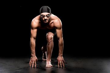 handsome swimmer standing in start position on black background