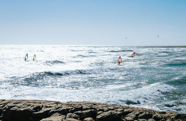 A group of Windsurfers riding the blue waves of a beach in the Cape of good hope National Park near Cape Town, South Africa