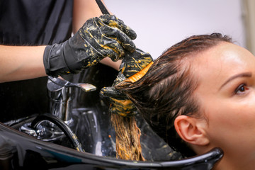 Girl in beauty salon while an hair stylist dyeing her hair