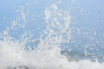 The wave breaks on the rock and forms a lot of spray