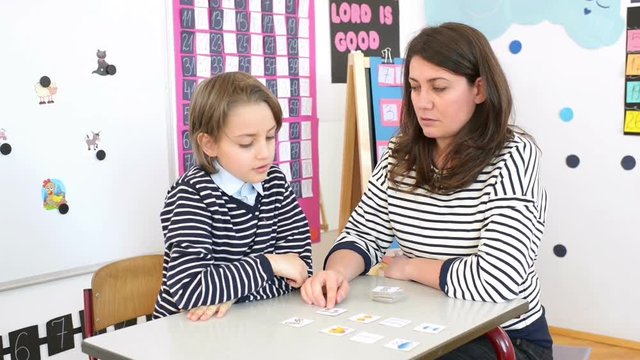 Cute boy and young woman speech therapist during private language lesson at office