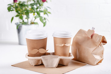 Two paper cups of coffee in cardboard tray on white background. Take out food. Cups with face of man and woman, couple in love, relations, love concept. Happy Valentine's day. Copy space.