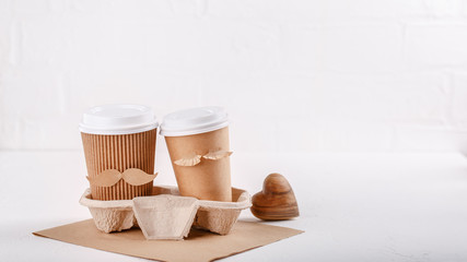 Two paper cups of coffee in cardboard tray on white background. Take out food. Cups with face of man and woman, couple in love, relations, love concept. Happy Valentine's day. Copy space.