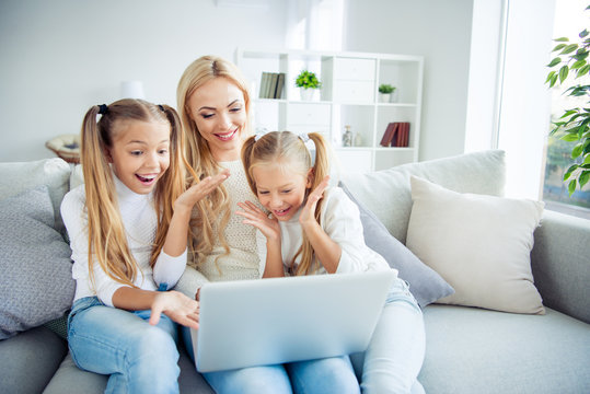 Portrait of three nice-looking cute lovely attractive cheerful cheery positive people pre-teen girls mom sitting on divan making video call w-fi in light white interior room indoors