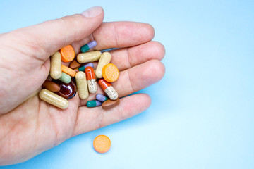 Tablets and pills on the palm of a person. An elderly man holds a lot of colored pills in old...