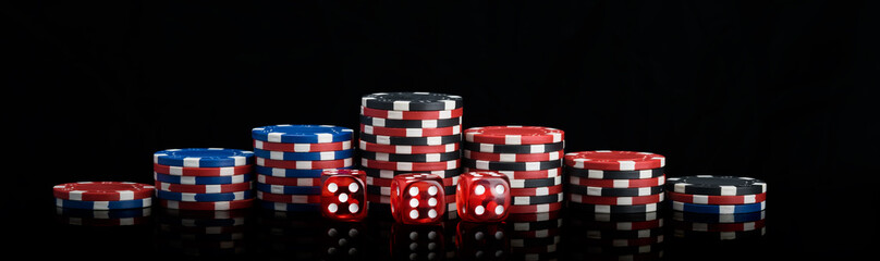 background vertical rows of different poker chips and red dice stand on a black background long photo