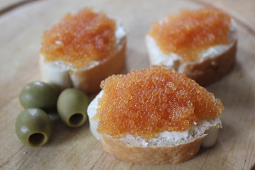Golden pike caviar on white bread with olives