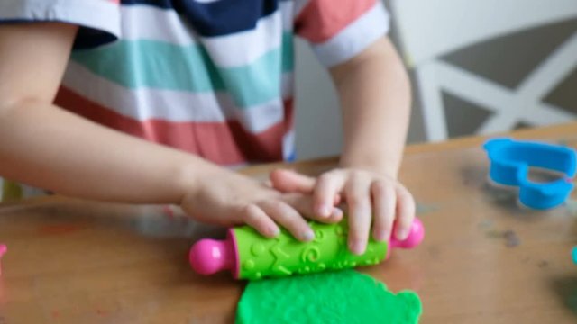 Lovely 4 years boy with playdough at home. Hands close up