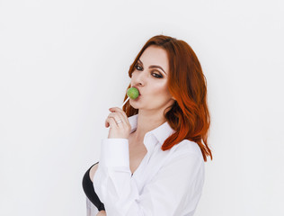 Portrait of a red-haired woman, breasts, sucks caramel on a stick, on a white background.