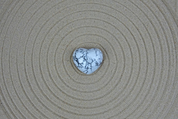 Heart of marble lying on the sand painted circles
