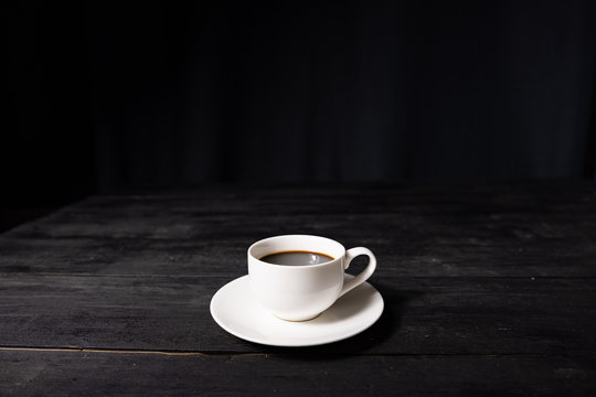 Cup Of Espresso Coffee On Vintage Black Table, Front View. Coffee In White Cup On Dark Background With Pleasant Old Wood Texture