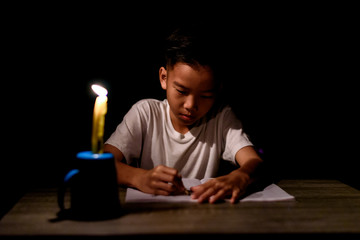 Young boy do home work under candle light