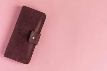 Female wine-colored wallet on pastel pink background. Flat lay. Copy space.
