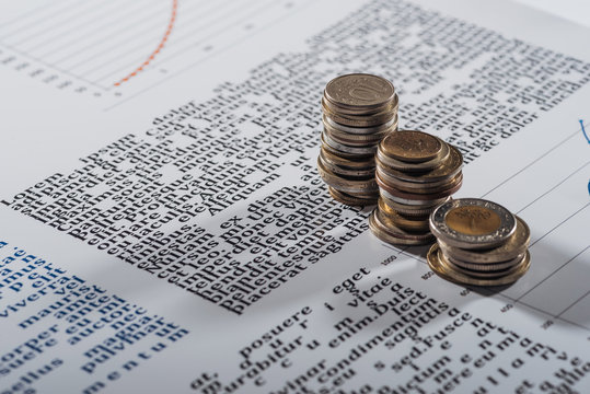 selective focus of coins stacks on text document with graphs