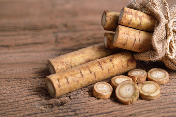 fresh burdock root or Gobo in sack and on wooden background - obrazy, fototapety, plakaty