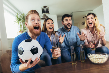 Happy friends or football fans watching soccer on tv and celebrating victory at home.Friendship, sports and entertainment concept.