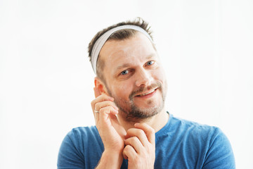 Man skin care. Attractive man put on a skin mask. Cosmetic procedures for men.