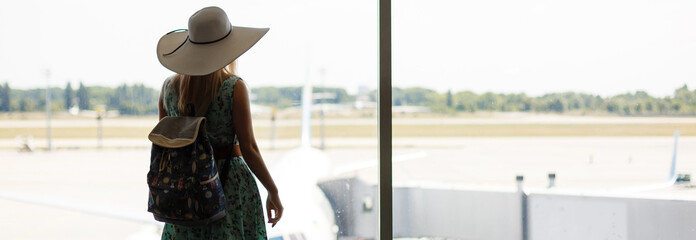 Vacation is beginning. Young woman in summer dress with backpack waiting for flight in modern...