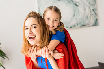 Hugging mother and kid in red cloaks looking at camera