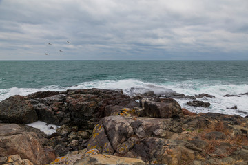 sea ​​scenery in dramatic weather in the blue hour. a landscape with dramatic clouds and stormy water that breaks down on the shore and the rocks.