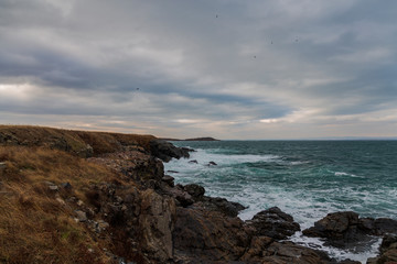 sea ​​scenery in dramatic weather in the blue hour. a landscape with dramatic clouds and stormy water that breaks down on the shore and the rocks.