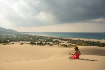 Fototapeta na wymiar Girl in red relaxing in sandy desert