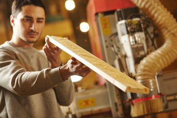 Man checks the evenness of grinding wood after CNC machine.