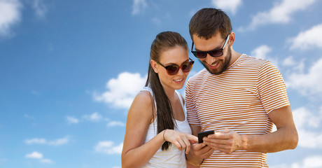 people, technology and lifestyle concept - happy couple with smartphone in summer