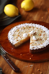 Chocolate Lemon Tart with hazelnuts and meringue cookies, on brown plate, on wooden table.