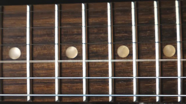 Close up of chords being strummed and vibrating during playing. Trembling guitar strings against fret. Beautiful background with wooden texture. Music performance. Slow motion