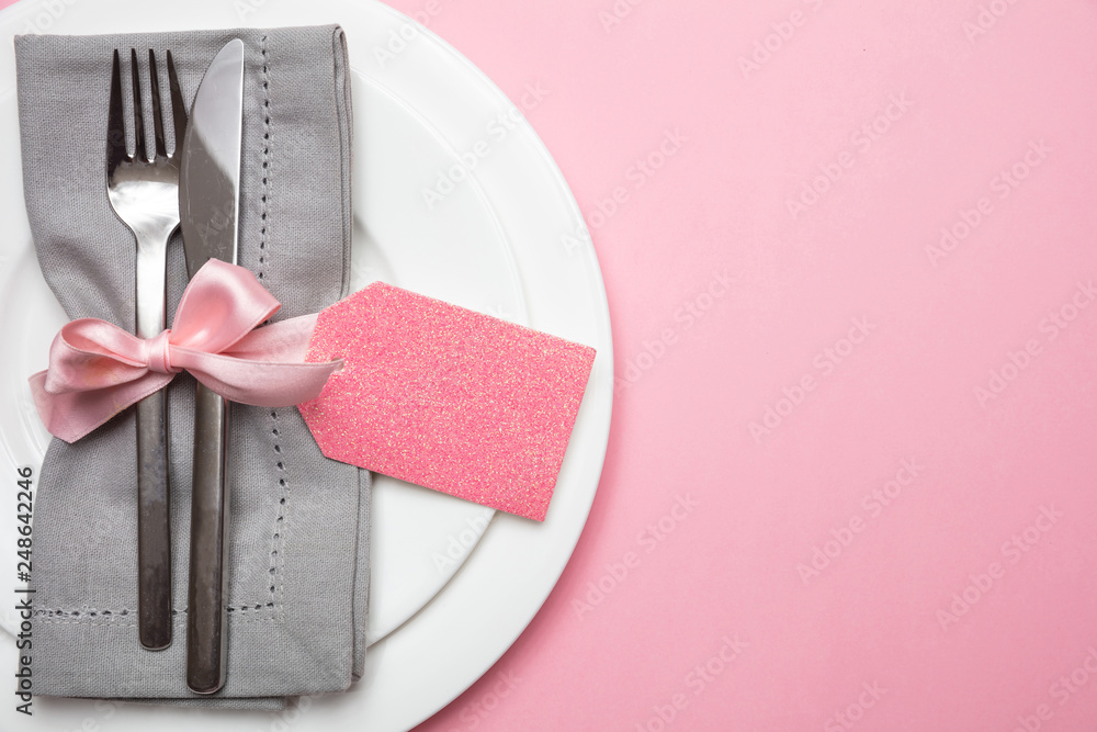Poster table place setting in pink. gray linen napkin with ribbon and and blank tag on pink color backgroun