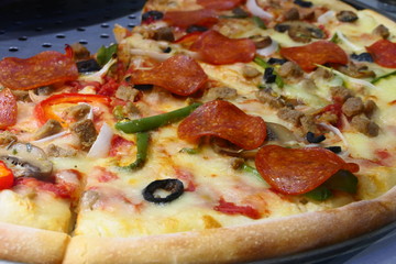 Close up view on a tasty Pizza with salami, beef, peppers, tomatoes, pepperoni and olives