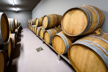 Wooden wine barrels stacked in modern winery cellar in Spain.