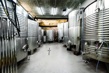 Inox wine barrels stacked in modern winery cellar in Spain.