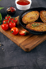 Close up view on burger, cutlets in pan, which stands on cutting board. Fried cutlets with cherry tomato, sauсe and spinach. food menu, recipe concept. Copy space