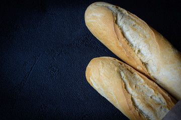 Macro view of freshly baked crunchy baguette bread on dark background. Closeup of crust of bread...
