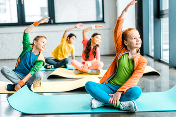 Happy kids stretching on fitness mats with smile