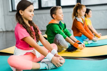 Foto op Canvas Smiling kids doing gymnastic exercises on fitness mats © LIGHTFIELD STUDIOS
