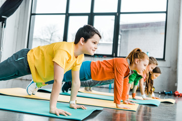 Obraz premium Preteen kids doing plank exercise together in gym