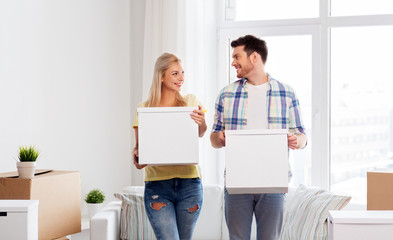 Fototapeta na wymiar mortgage, people and real estate concept - happy couple with boxes moving to new home